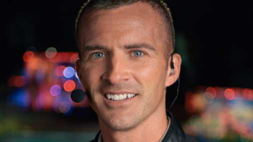 Nick White, founder of Off Leash K9 Training, in a close-up bio headshot with blurred colorful lights behind him, on the Charlottesville, VA site.